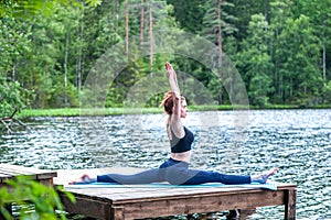Young yogi  girl  practicing yoga, stretching in Monkey God exercise, Splits, Hanumanasana pose on the lake. The concept of
