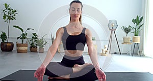 Young yogi woman meditating in the lotus position in a yoga studio. Meditation, yoga, mindfulness