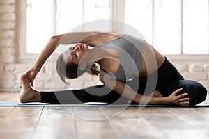 Young yogi woman in Parivrtta Janu Sirsasana pose