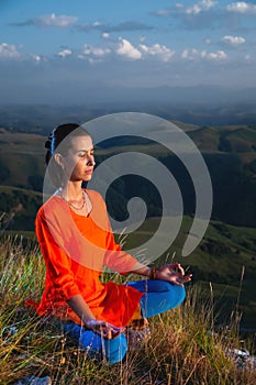 young yogi woman practicing meditation with closed eyes in lotus position at sunset