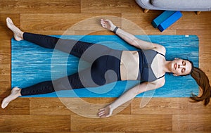 Young yogi woman relaxing in shavasana pose home photo