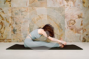 Young yogini practicing Janusirsasana pose in pastel blue leggins and top