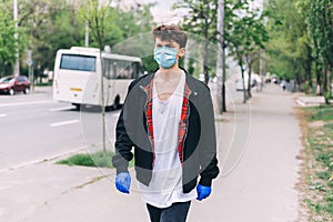 A young young man in a protective mask and gloves walks down the street