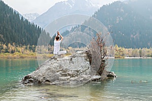 Young zen man in meditation. Outdoor yoga in mountain lake. Exercise Agni Stambhasana photo