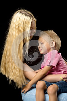 Younger brother with older sister in the studio on a black background.