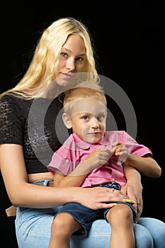 Younger brother with older sister in the studio on a black background.