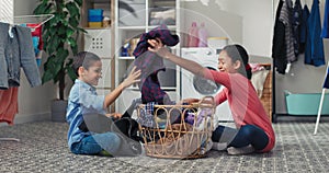 Younger brother and sister sort the clothes to be washed by appropriate colors, spending time in the laundry room doing