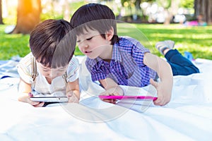 Younger brother watching movie or playing games on tablet and ignoring his older brother. Older brother peeking his little boy tha