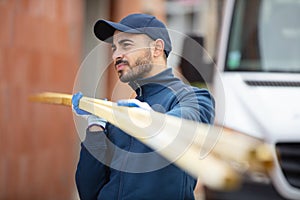 younger carpenter holds wooden planks