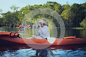 Younger woman taking photo by mobilephone while sailing sea kayak