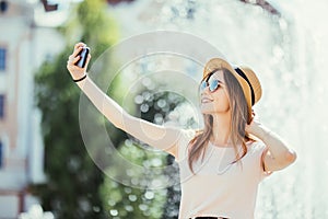 Youngpretty girl take selfie from hands with phone on summer city street. Urban life concept.