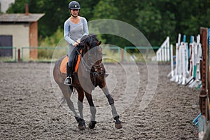 Young girl riding bay horse on equestrian sport training