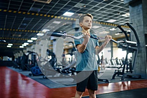 Youngster doing exercise with bar in gym