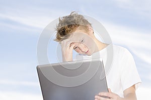 Youngster with laptop against blue sky