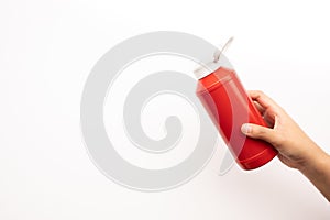 Youngwoman hand squeezing bottle of tomato sauce ketchup on white background