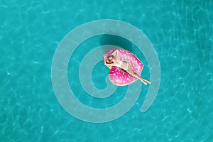 Youngwoman with inflatable ring in swimming pool, top view. Summer vacation