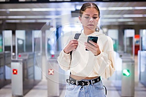 Younh female passing the turnstiles at subway station