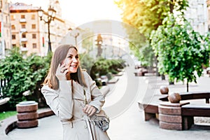 Younng woman talking phone at city street. Petty businesswoman speaking mobile. Business lady call phone. Pleasant