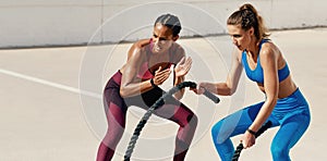 Your achievement is worth those tough lessons. Shot of sporty young woman doing heavy rope training with her trainer.