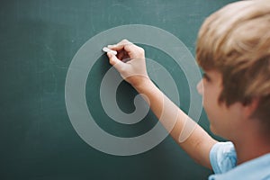 Your copys what hes writing. A young boy writing on a blackboard with a piece of chalk - copyspace.