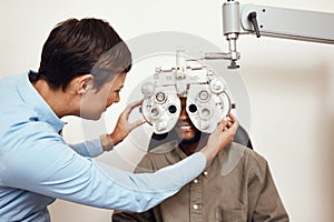 Your eyes are too important not to get them checked. Shot of an optometrist examining her patients eyes with an optical