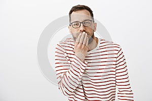 Your face make me puke. Portrait of disgusted european guy feeling unwell, covering mouth with palm and feeling dizzy