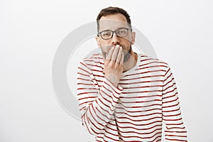 Your face make me puke. Portrait of disgusted european guy feeling unwell, covering mouth with palm and feeling dizzy photo