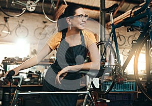 Your friendly neighborhood bike specialist. a young woman working in a bicycle repair shop.