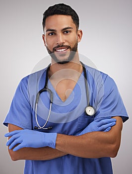 Your health rests in good hands. a handsome young nurse standing alone in the studio with his arms folded.