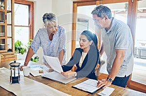 Your investments are looking quite profitable. a mature couple getting advice from their financial consultant at home.