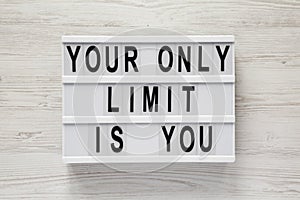 `Your only limit is you` word on lightbox on a white wooden background, top view. From above, flat lay, overhead