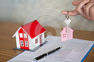 Your new house, real estate agent holding house key to his client after signing contract agreement in office,concept for real