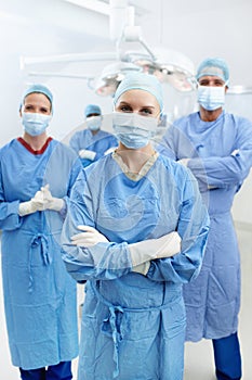 By your side every step of the way. Portrait of professional surgeons with face masks and hospital scrubs standing in an