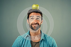 Your target should be a healthier lifestyle. Studio shot of a handsome young man posing with an apple on his head