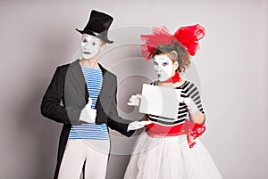 Your text here. Actors mimes holding empty blank board. Colorful studio portrait with gray background. April fools day