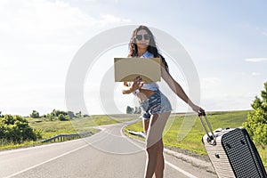 Your text here.Travel and hitch-hiking concept. portrait of happy pretty young woman standing with empty blank. woman on