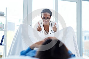 Youre doing great. a young gynaecologist giving a thumbs up during a consultation with her patient. photo