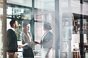 Youre going to love working here. businesswomen shaking hands in a modern office.