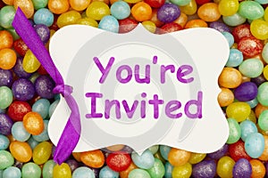 Youre invited message on a gift tag over colorful jellybean candy photo