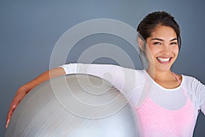 Youre one workout away from a good mood. a sporty young woman holding a pilates ball against a grey background.