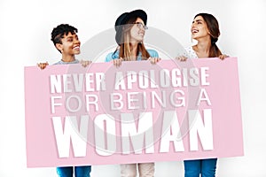 Youre a woman, that is your strength. Studio shot of young women holding a placard with the words never apologise for