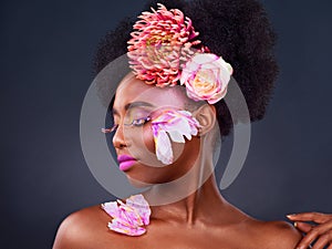 Youre a work of art. Studio shot of a beautiful young woman posing with flowers in her hair.