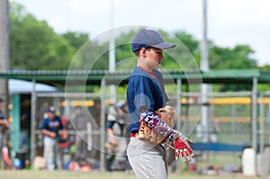 Youth baseball player walking off the field during game.