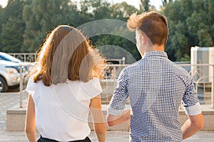 Youth boy and girl back view walking talking outdoor