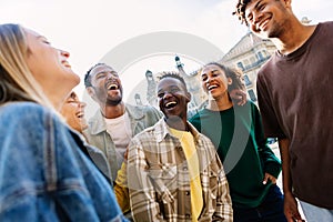 Youth group of multiracial student friends laughing together hanging out outside