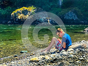 Youth by ice cold river in Pacific Northwest wilderness