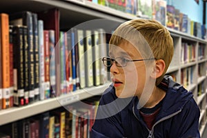 Youth at library surrounded by shelves of books