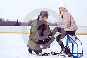 Youth Lifestyle Ideas. Happy Caucasian Couple in Winter With Ice Skates Posing Together On Snowy Skatingrink while Man Help To