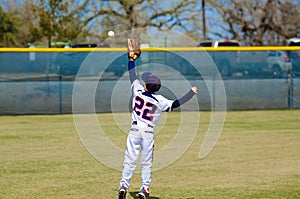 Youth outfielder catching ball
