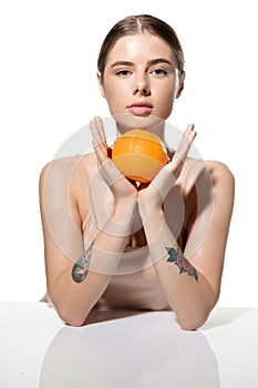Youth secrets. Beautiful young woman with orange over white background. Cosmetics and makeup, natural and eco treatment